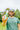 man wearing a rubber ducky sunscreen hat outside holding up mineral sunscreen lotion for face