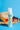 rubber ducky mineral sunscreen on a blue background in front of a beach hat